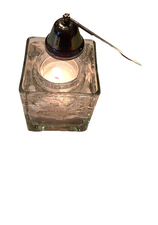 Photophore en verre texturé avec une bougie allumée à l’intérieur, accompagné d’un éteignoir noir avec une poignée reposant sur son bord