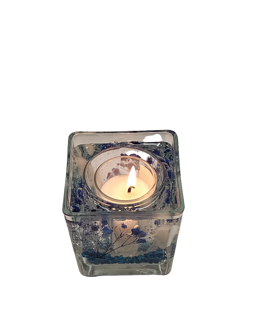 Photophore en verre avec des motifs bleus et des perles bleues, contenant une bougie allumée, créant un contraste lumineux.