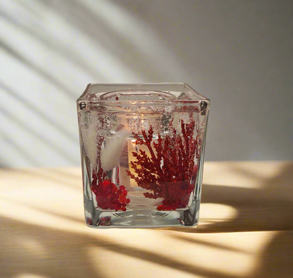 Photophore en verre transparent avec décorations rouges, créant une ambiance chaleureuse et élégante.